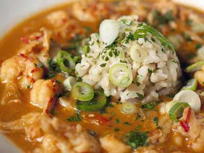 A bowl of rice and meat covered in sauce.