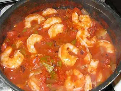 A pan of shrimp and tomato sauce in the middle of cooking.