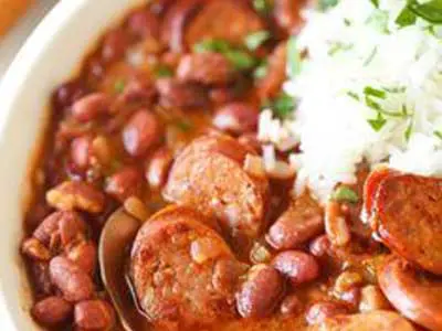 A bowl of beans and rice with sausage.