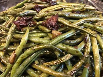 A close up of some green beans with bacon