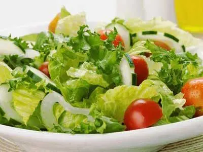 A bowl of salad with lettuce, tomatoes and onions.