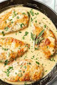 A pan of chicken covered in sauce with herbs.