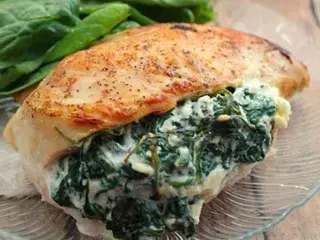 A piece of chicken with spinach on top.